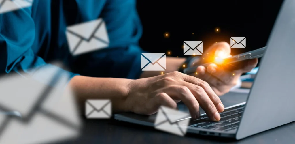 Business professional using laptop and smartphone with digital email icons representing newsletter engagement.