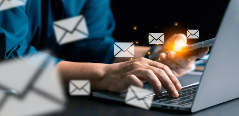Business professional using laptop and smartphone with digital email icons representing newsletter engagement.